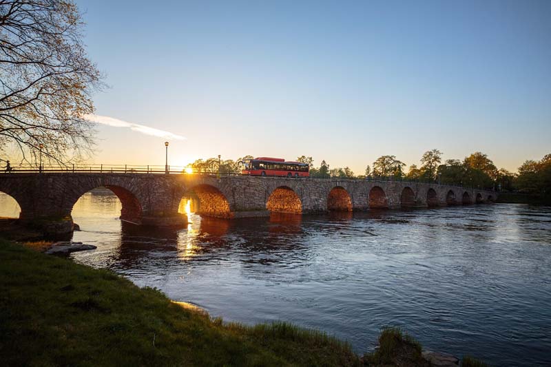 Stenbron över Klarälven i Karlstad belyst av solnedgång