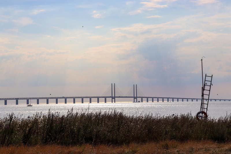 Öresundsbron sedd från Malmös kust med blå himmel och glittrande hav