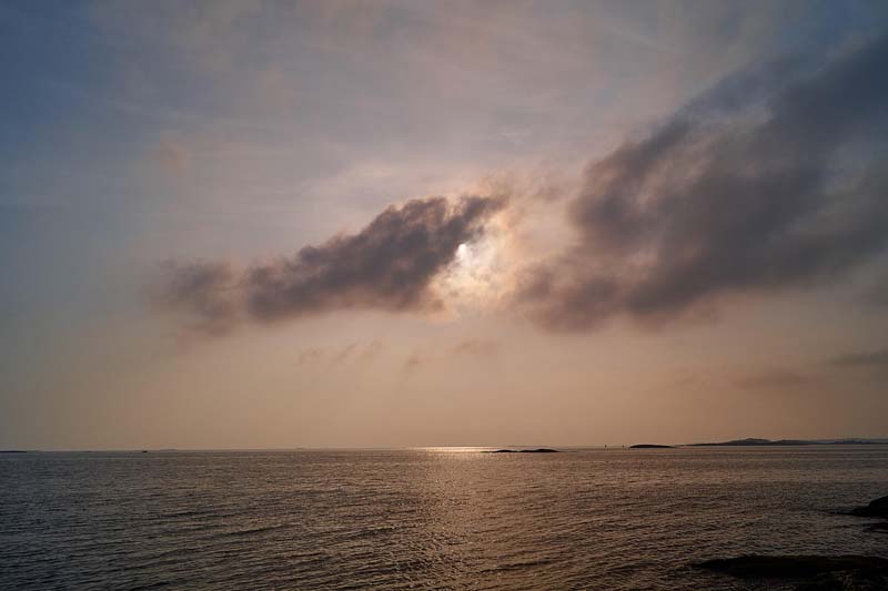 Solnedgång över Nynäshamns skärgård med båtar i hamnen